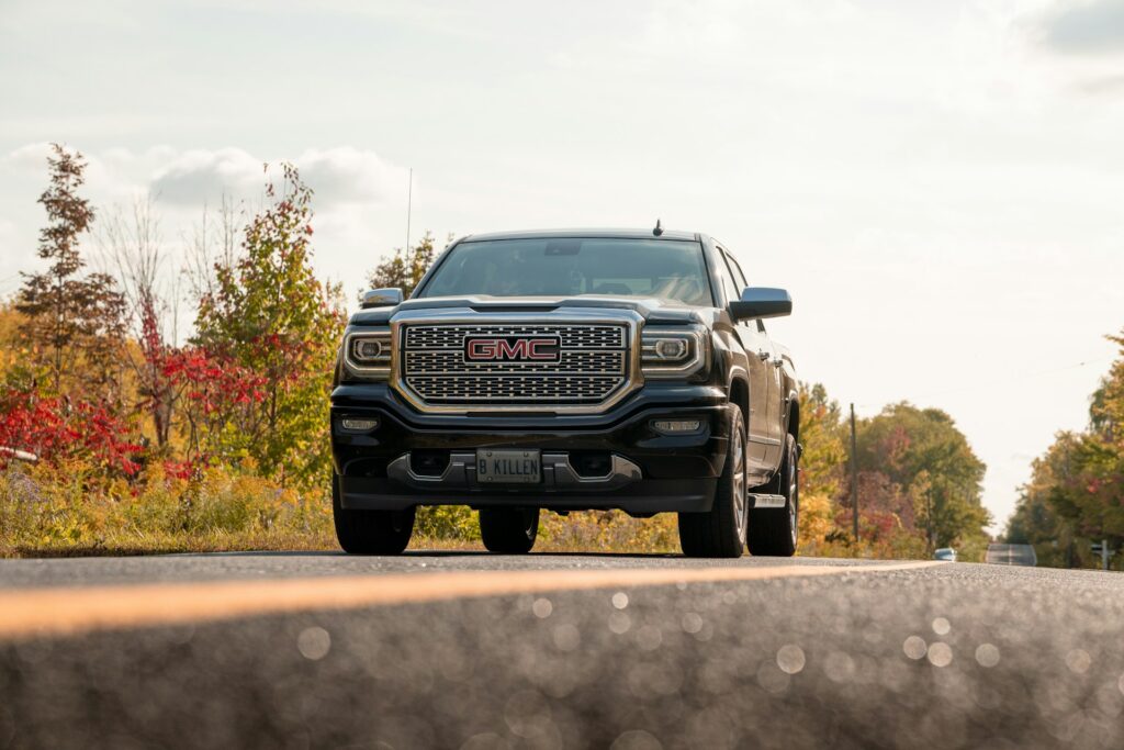 A black GMC Sierra 1500 truck driving on a road with trees in the background.