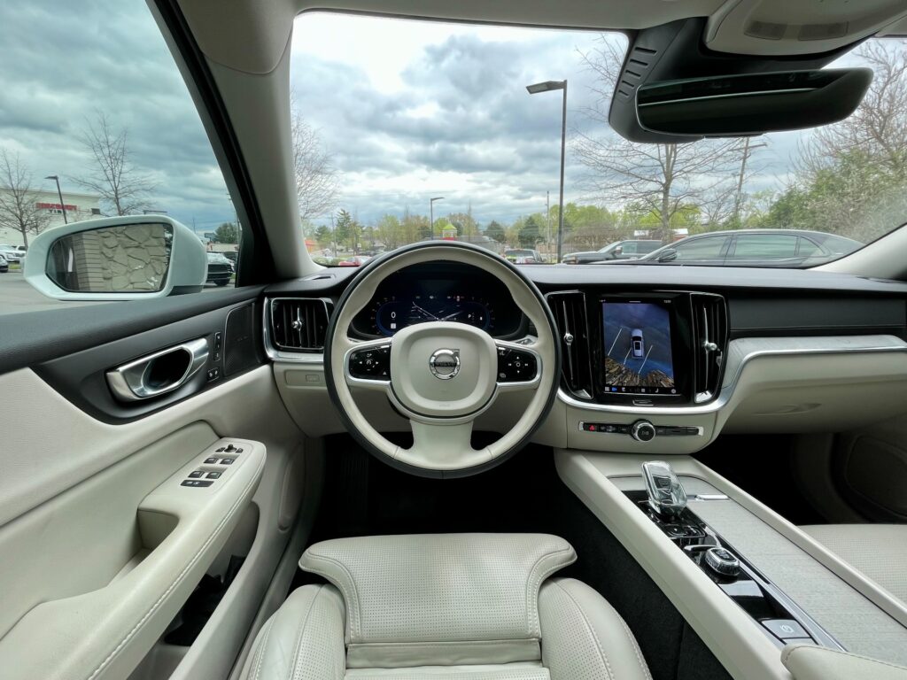 A comfortable and stylish interior of a Volvo V60 Cross Country wagon with light colored leather seats and a large touchscreen in the center console.