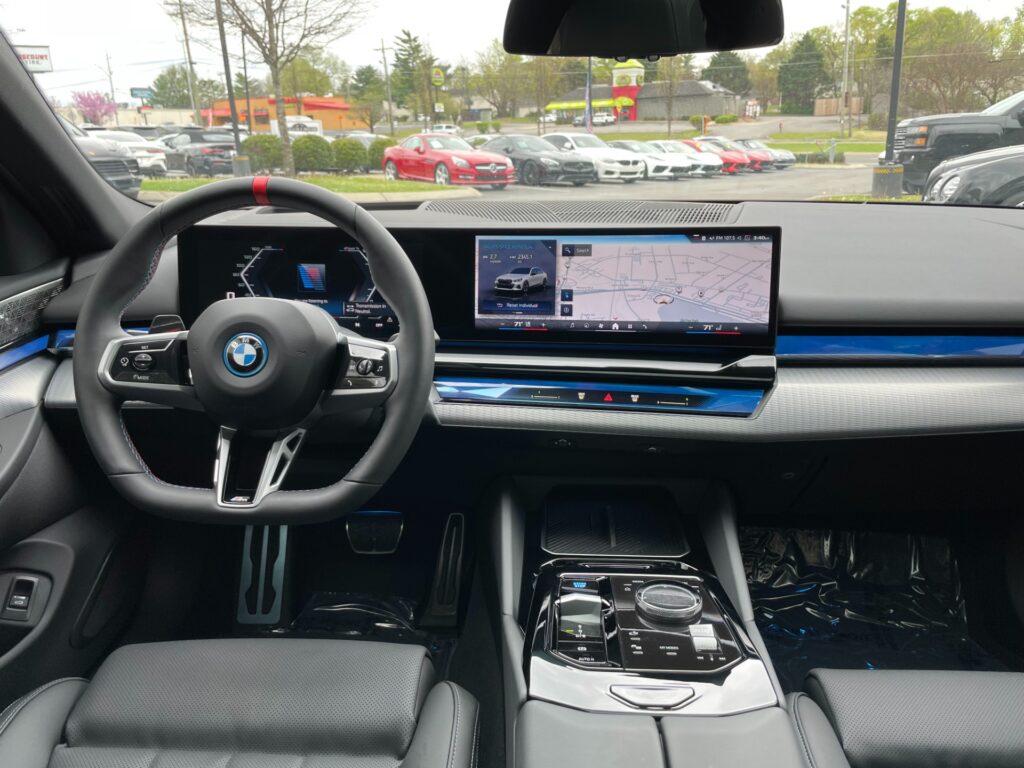 A photorealistic image of the interior of a new BMW i4 electric car. The interior is white with black accents and has a large curved display screen in the center of the dashboard.