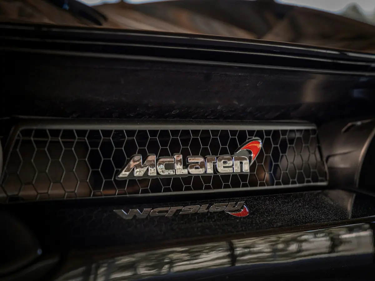 Close-up of the McLaren logo on a hexagonal grille, symbolizing precision engineering and supercar performance.
