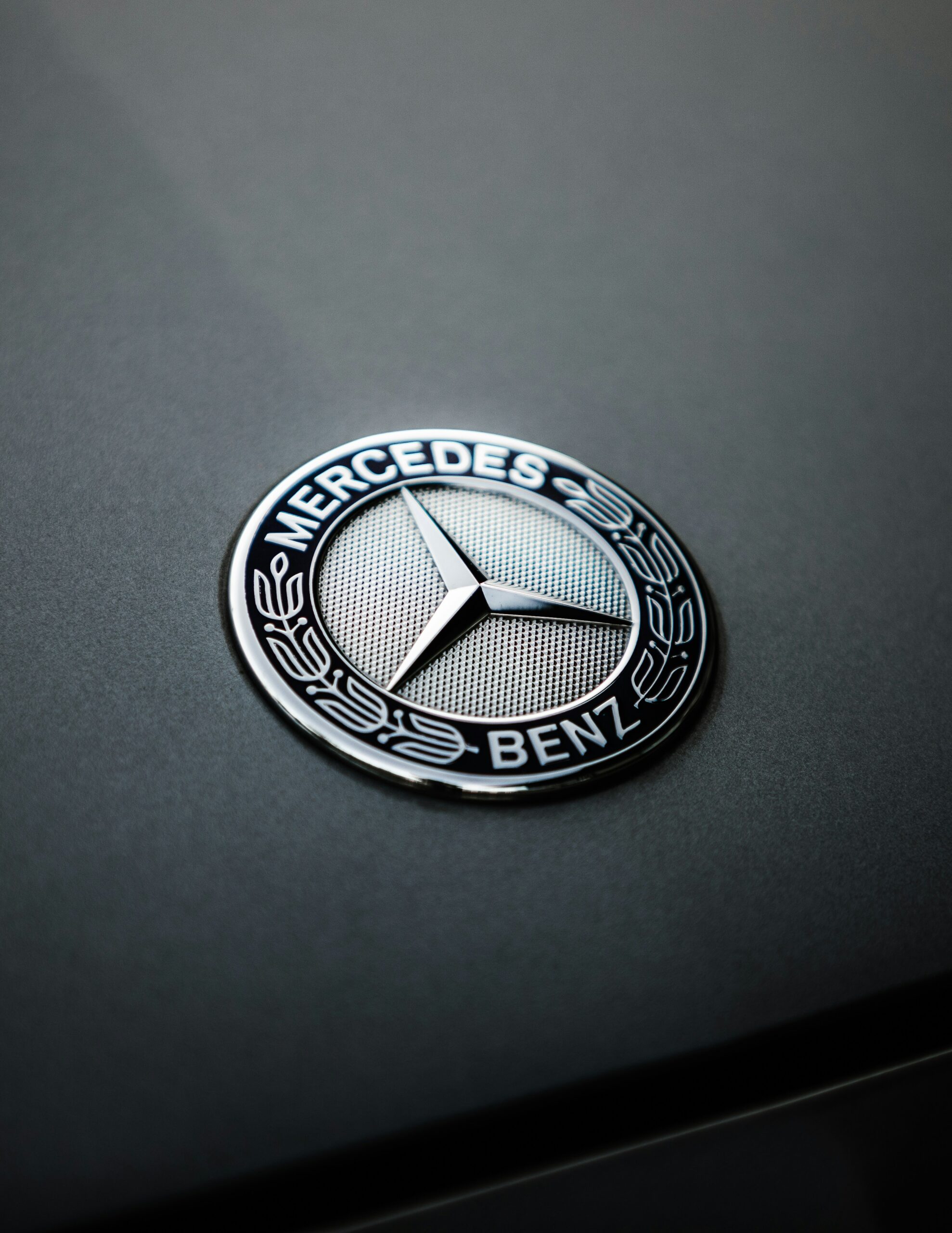 Close-up of the Mercedes-Benz logo emblem with chrome finish on dark surface.