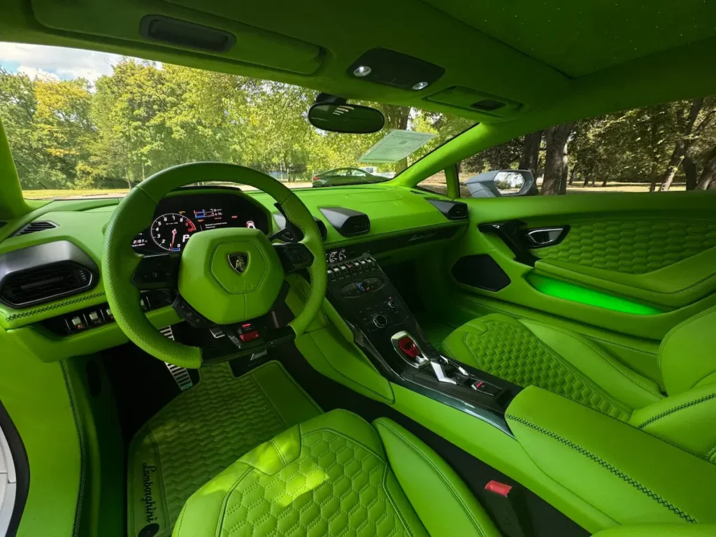 Lamborghini Huracán interior driver view with green steering and digital display.