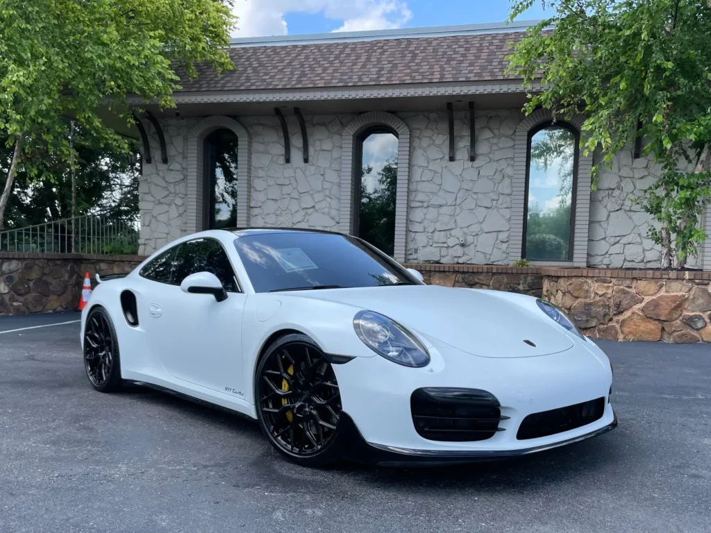 Used 2015 Porsche 911 Turbo Premium Plus Sport in white, parked in front of a building.