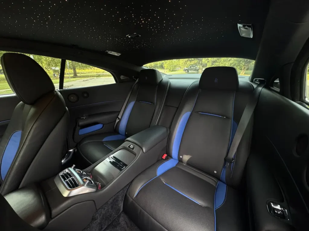 Rear seating area of 2016 Rolls-Royce Wraith with black and blue leather and starlight headliner.