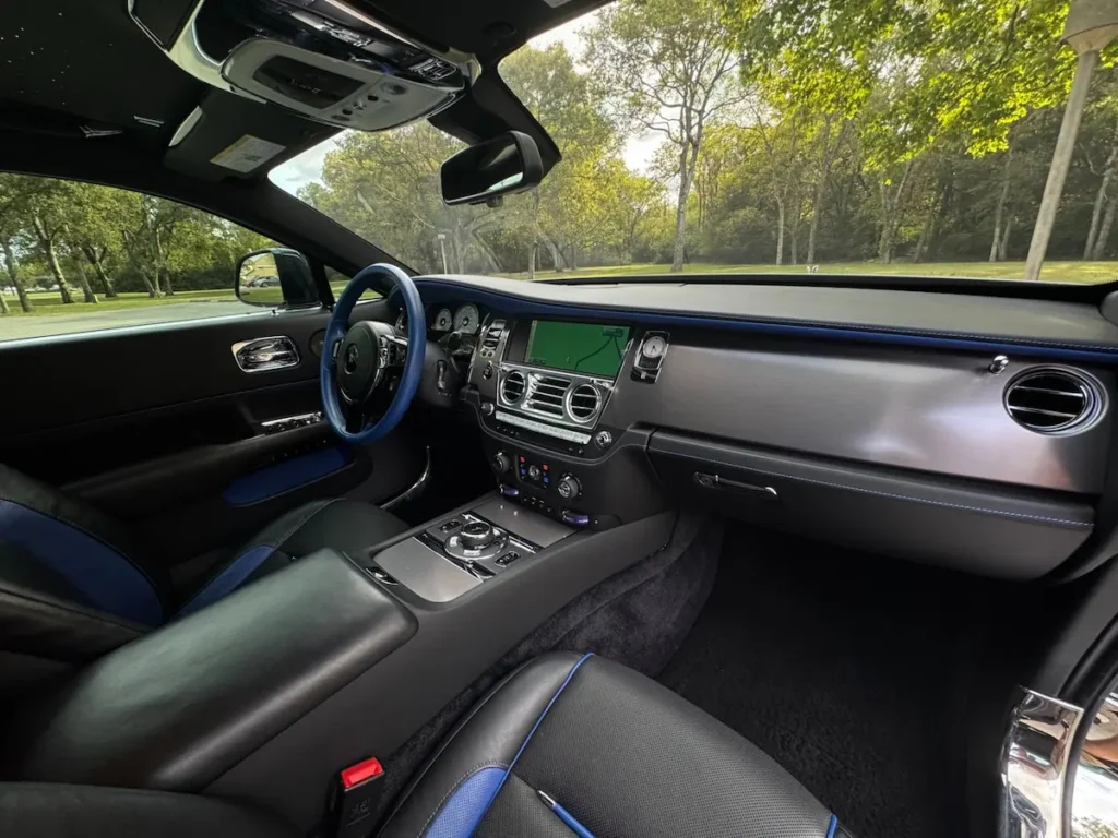 Interior of 2016 Rolls-Royce Wraith featuring black leather seats, blue accents, and chrome center console.