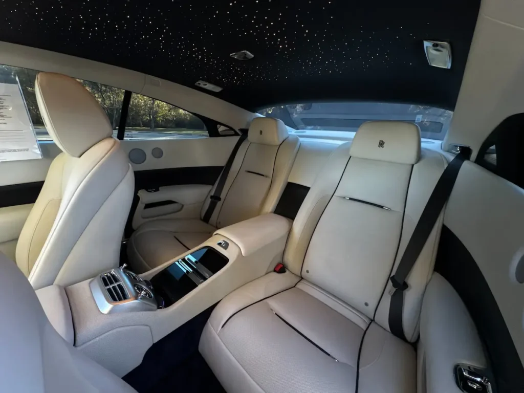 Rear seats of Rolls-Royce Wraith under starlight headliner with cream leather trim.