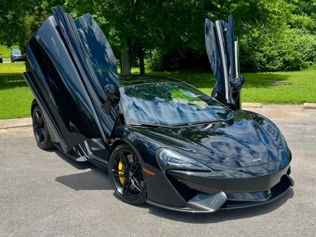 McLaren 570S in gloss black with dihedral doors raised, highlighting lightweight carbon-fiber design.