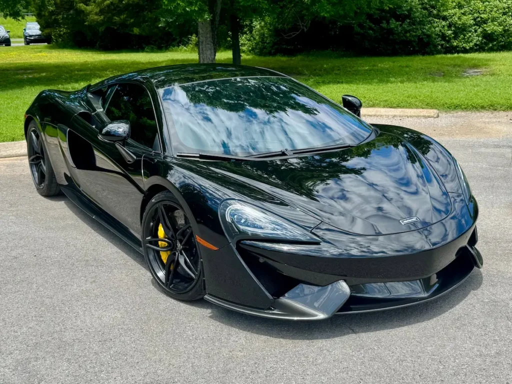 Front three-quarter view of a black McLaren 570S showcasing sleek lines and yellow brake calipers.