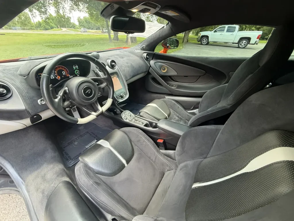 Interior of a McLaren 570S showcasing Alcantara seats, minimalist dash, and driver-focused cockpit.