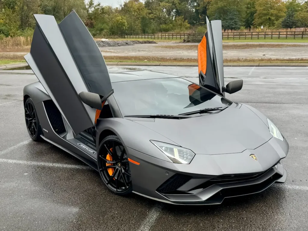 Matte gray Lamborghini Aventador LP 740-4 S with open doors in a parking lot.