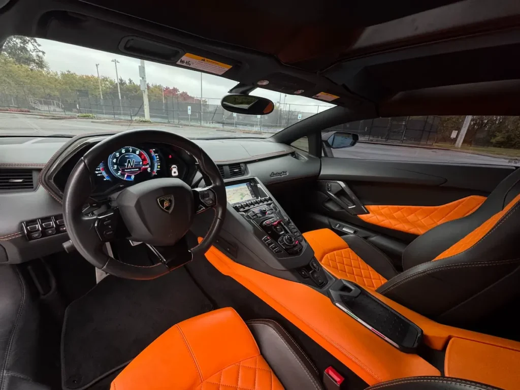 Interior view of 2018 Lamborghini Aventador with orange and black quilted leather seats.