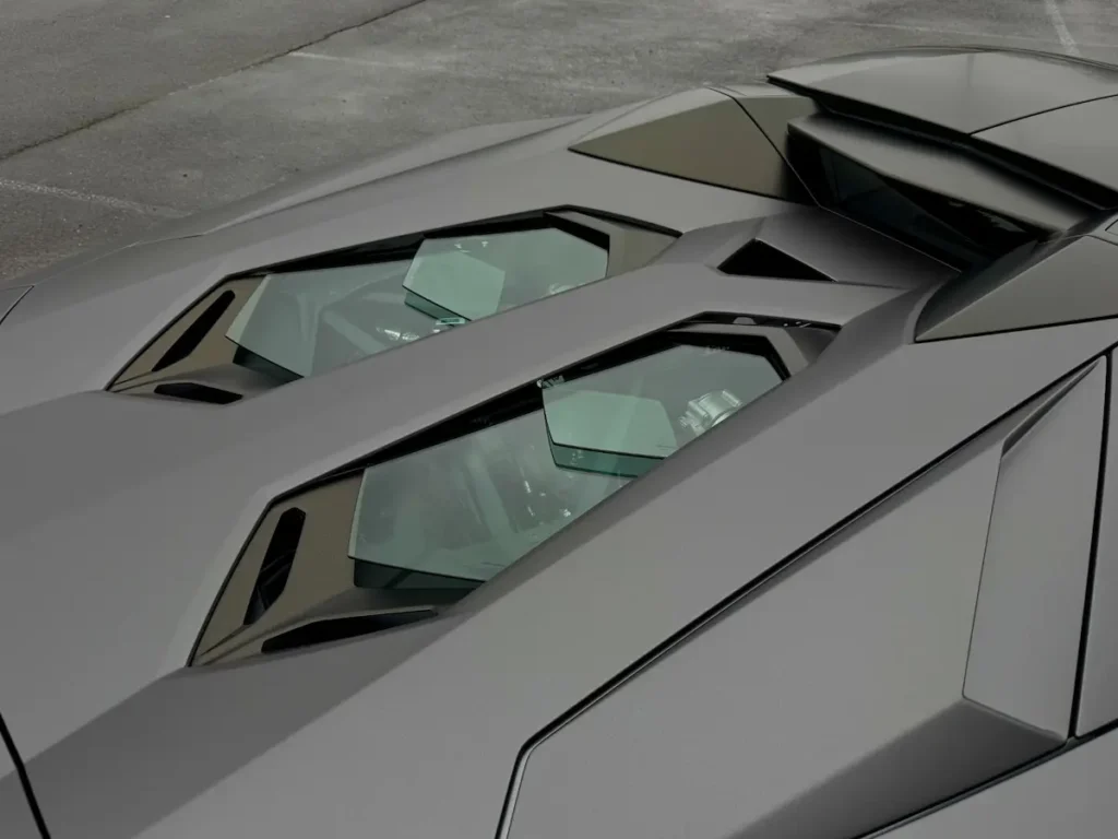 Close-up of Lamborghini Aventador V12 engine under glass engine cover.