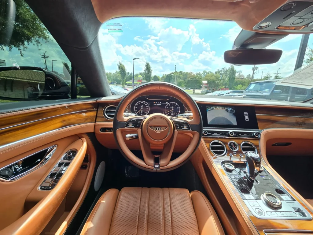 Luxurious tan leather interior of a Bentley Continental, featuring a wooden dashboard and modern tech amenities, photographed at AutoPro Nashville.