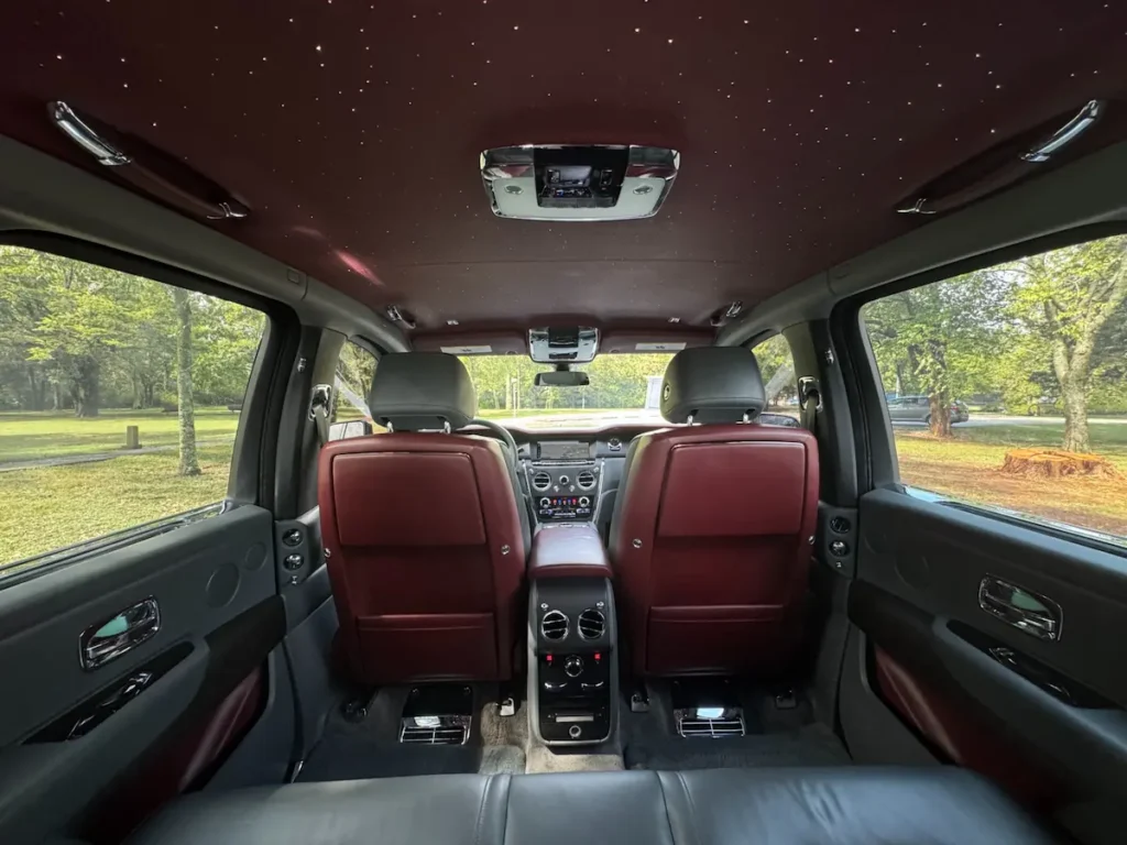 Rear interior of Rolls-Royce Cullinan with red and black leather under starlight roof.