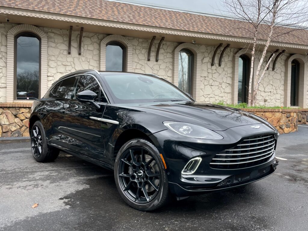 A black Aston Martin DBX SUV parked in front of a stone building