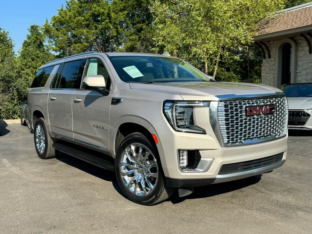 Front-side view of a 2023 GMC Yukon Denali in Pearl Beige Metallic, highlighting its chrome grille, LED headlights, and premium design.
