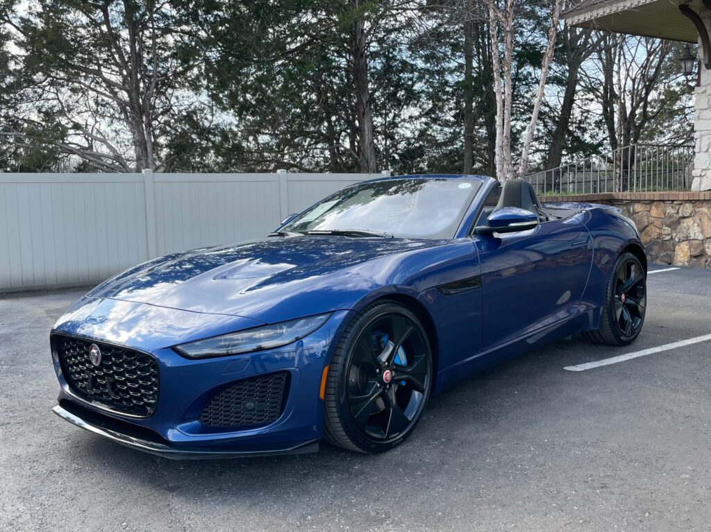 A blue 2021 Jaguar F-Type convertible parked in a dealership showroom.