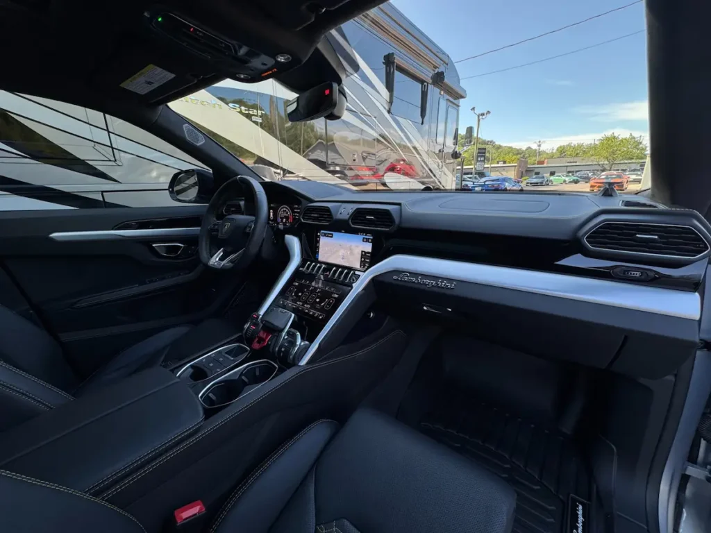 Passenger view of Lamborghini Urus interior with carbon-fiber trim and black leather seats.
