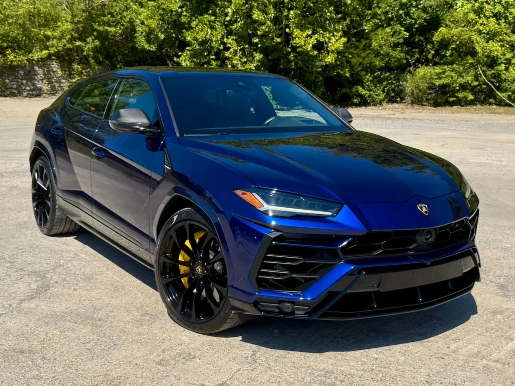 2021 Lamborghini Urus in metallic blue parked outdoors, showing its bold grille and black alloy wheels.
