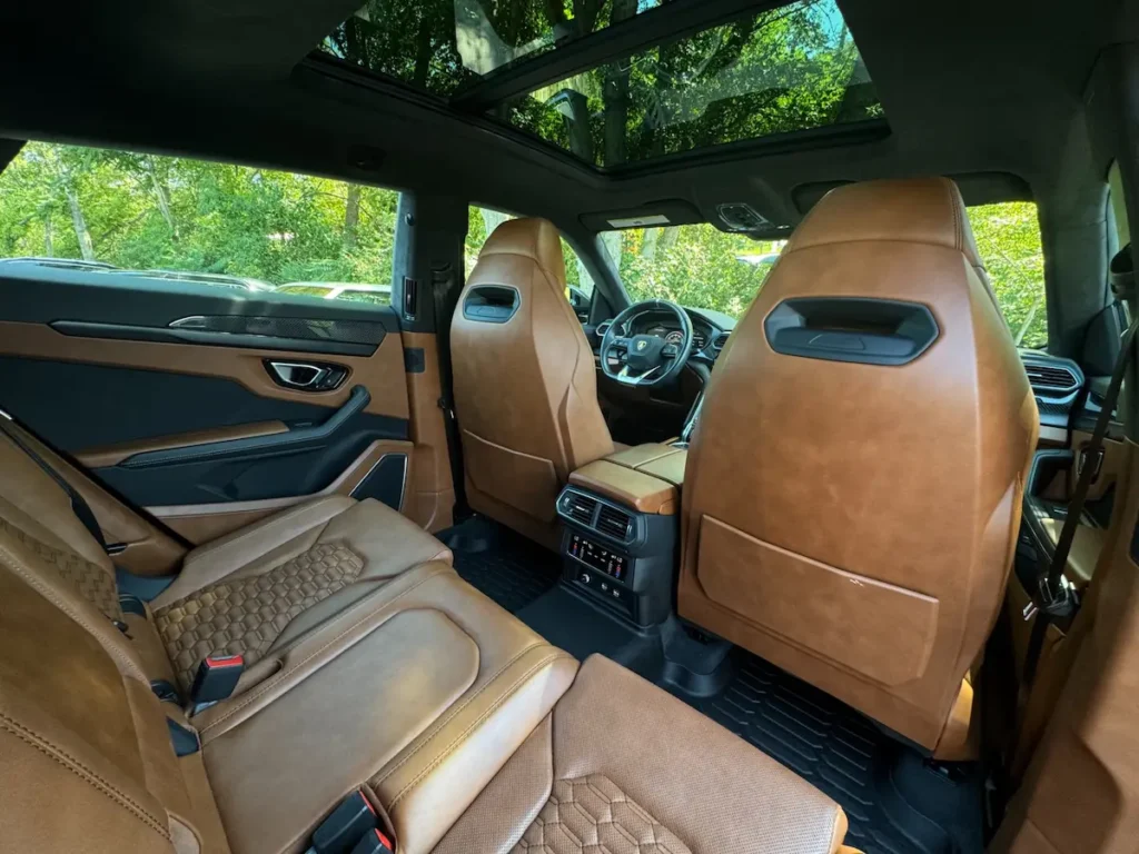 Rear seat view of Lamborghini Urus with tan leather upholstery and panoramic roof.