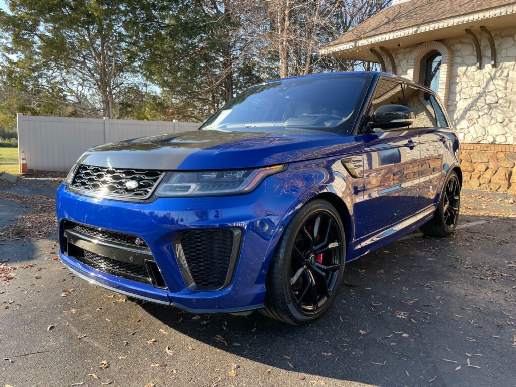  A blue 2021 Land Rover Range Rover Sport SVR Carbon Edition parked on the showroom floor at AutoPro Nashville, a used car dealership.