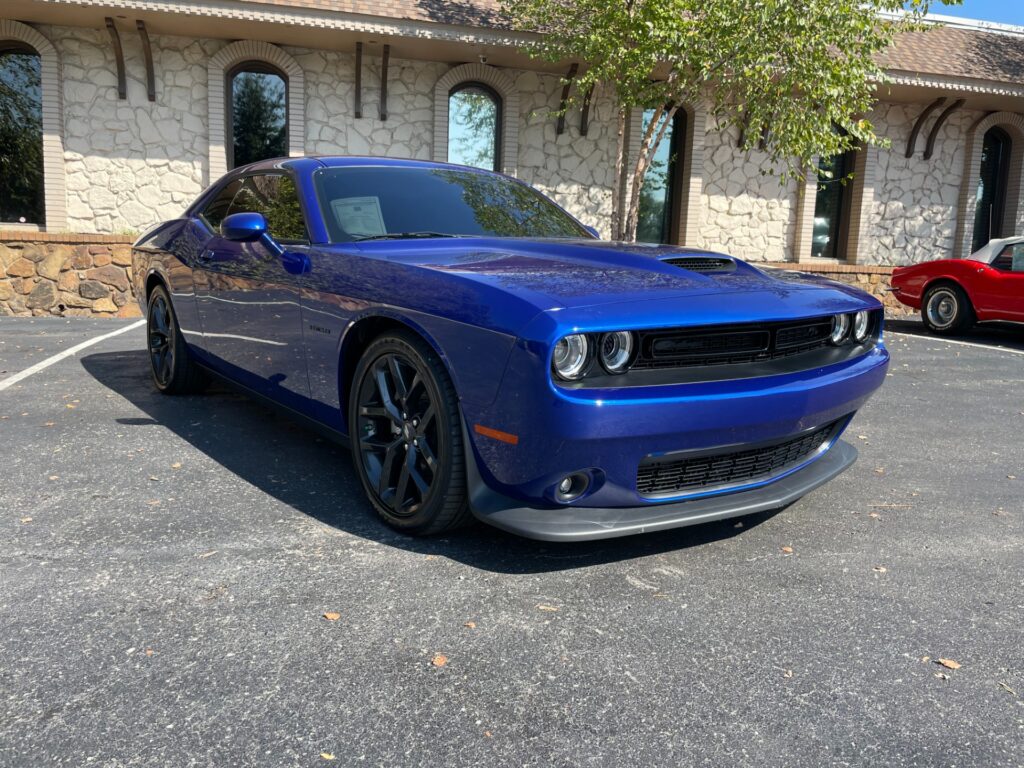 A blue Dodge Challenger R/T parked in the showroom of AutoPro Nashville, a used car dealership.