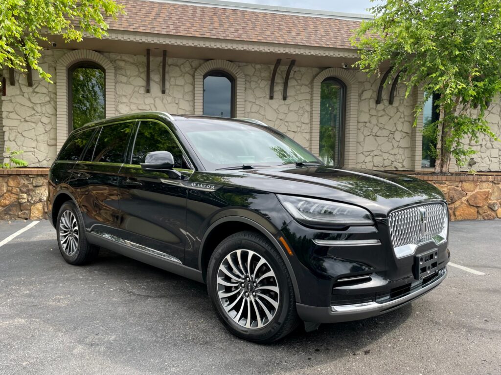 Sleek black Lincoln Aviator SUV parked in front of a modern dealership building with a black metal awning. Available for test drive at AutoPro Nashville.