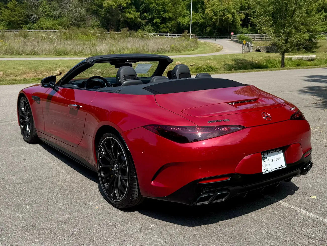 Rear three-quarter view of the 2022 Mercedes-AMG SL63 Roadster with soft top down, black wheels, and quad exhausts.