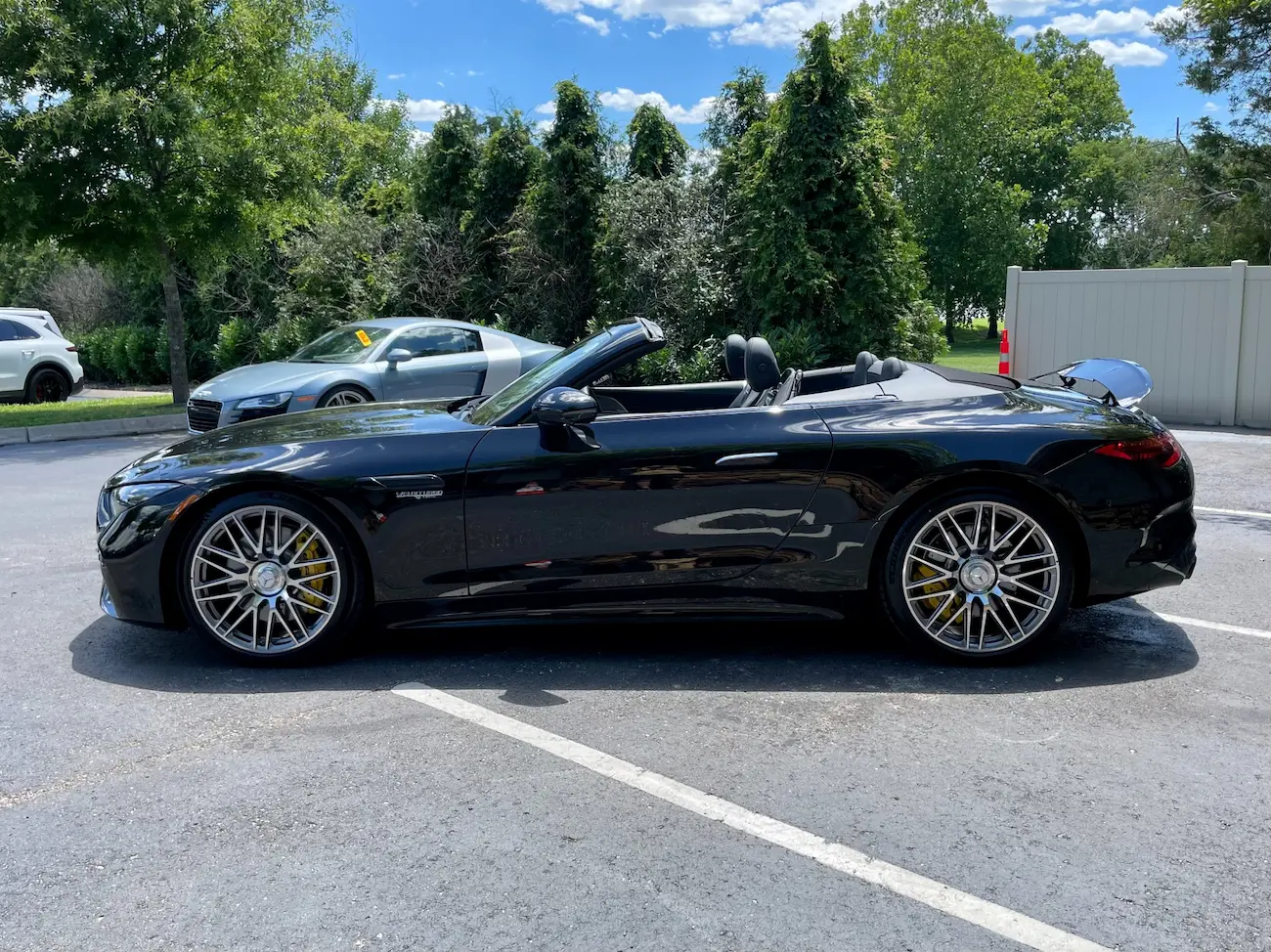 Side profile of a black 2022 Mercedes-AMG SL 63 Roadster with roof down, parked outdoors.