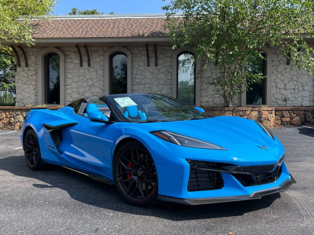 Front exterior view of a blue 2023 Chevrolet Corvette Z06 Convertible parked outside, showcasing its aerodynamic design.