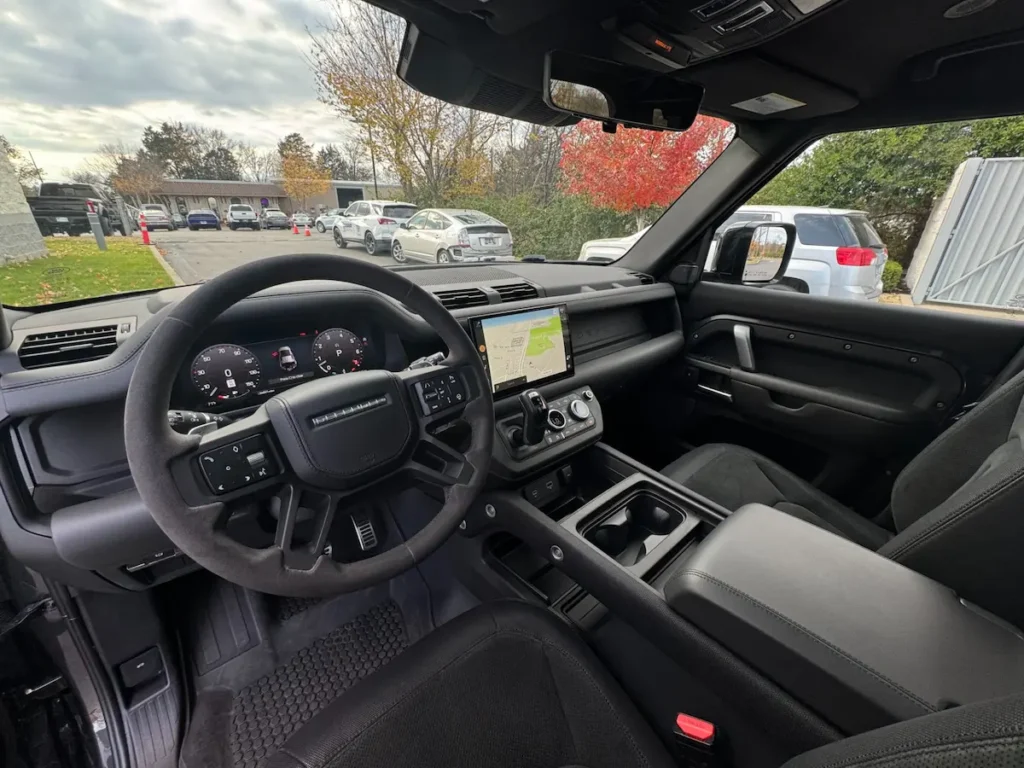 Interior cabin of a 2023 Land Rover Defender 110 V8 with digital displays and rugged design.