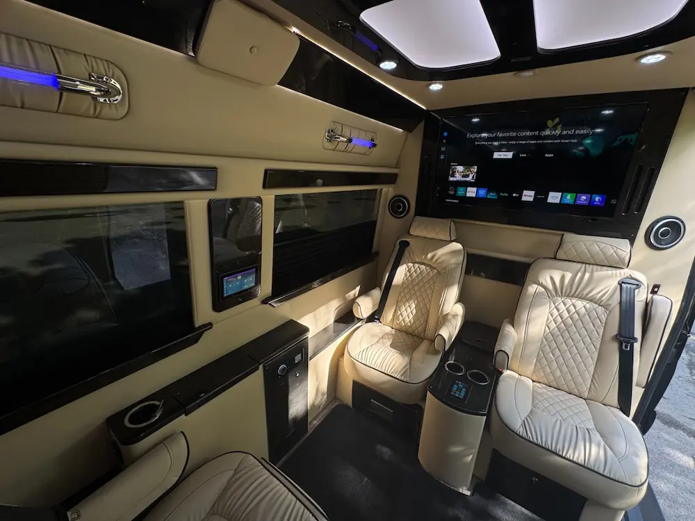 Rear cabin of 2023 Mercedes-Benz Sprinter 3500XD Ultimate Limo with diamond-stitched leather seating and large TV display.