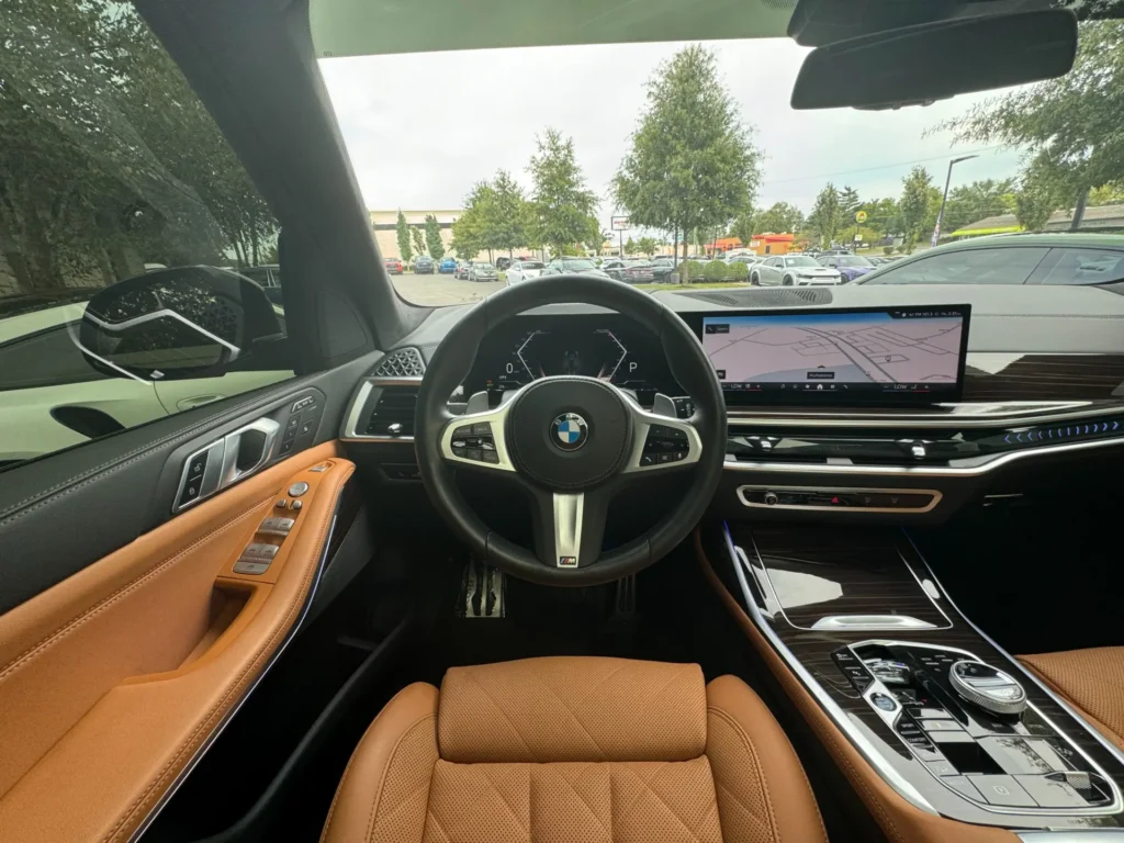 Luxurious interior of a used 2024 BMW X7 xDrive40i with tan leather seats and high-tech dashboard.