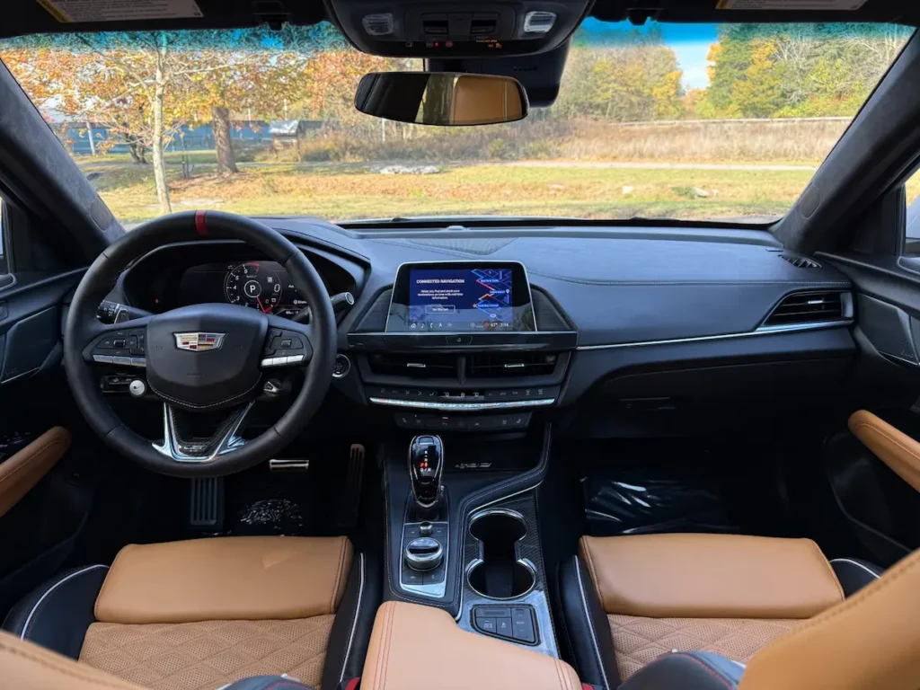 2024 Cadillac CT4-V Blackwing cockpit with digital cluster, sport steering wheel, and carbon fiber trim.