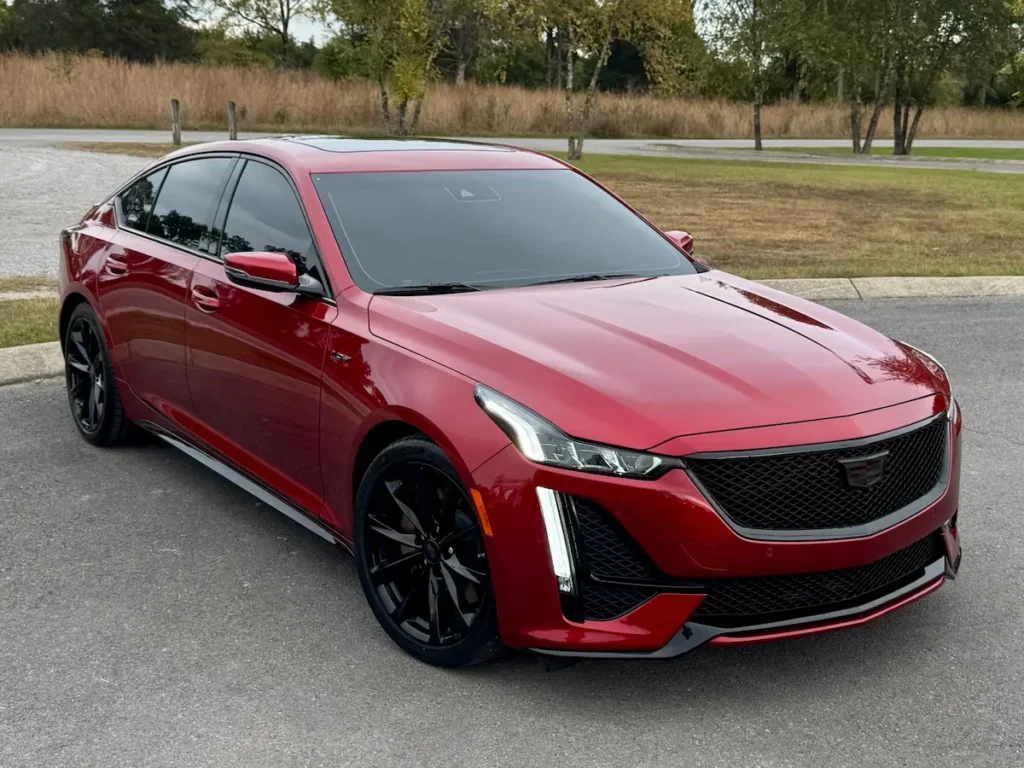 2024 Cadillac CT5-V front three-quarter view in red showing bold mesh grille, LED lighting, and aerodynamic design.