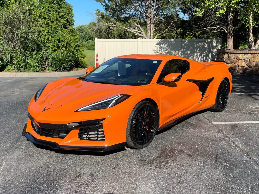 Front exterior view of an orange 2024 Chevrolet Corvette Z06 Coupe, emphasizing its aggressive stance and sporty design.