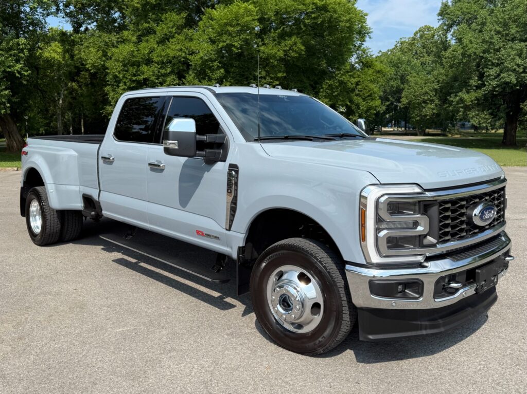 Front three-quarter view of a 2024 Ford F-350 Super Duty Platinum in white featuring chrome grille and dual tow mirrors