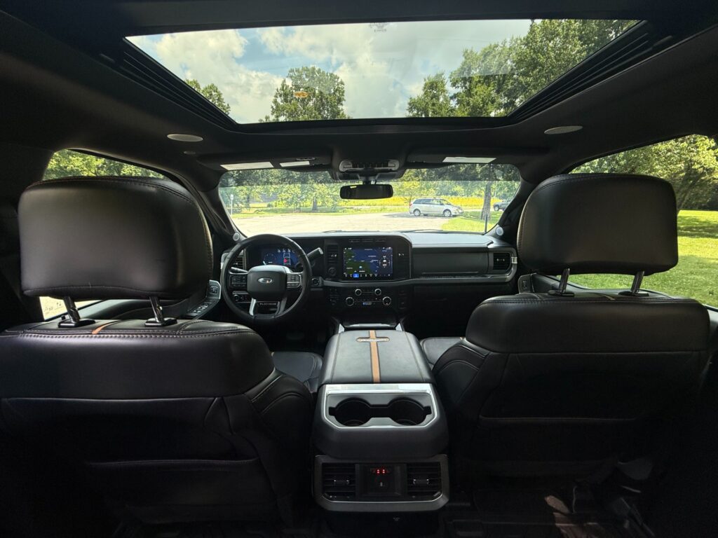 Interior view of a 2024 Ford F-350 Super Duty Platinum with black leather seats, panoramic moonroof, and advanced infotainment system.