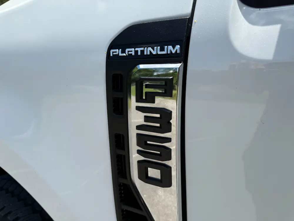 Close-up of a Ford F-350 Platinum badge on a white truck, showing the chrome and black side emblem design.