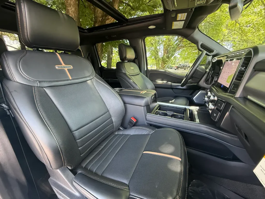Front leather seats of 2024 Ford F-350 Platinum Super Duty with orange accent stitching and logo detailing.