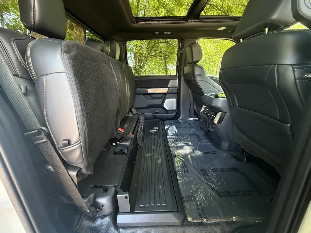 Rear seat area of 2024 Ford F-350 Platinum Super Duty with seats folded for extra cargo space.
