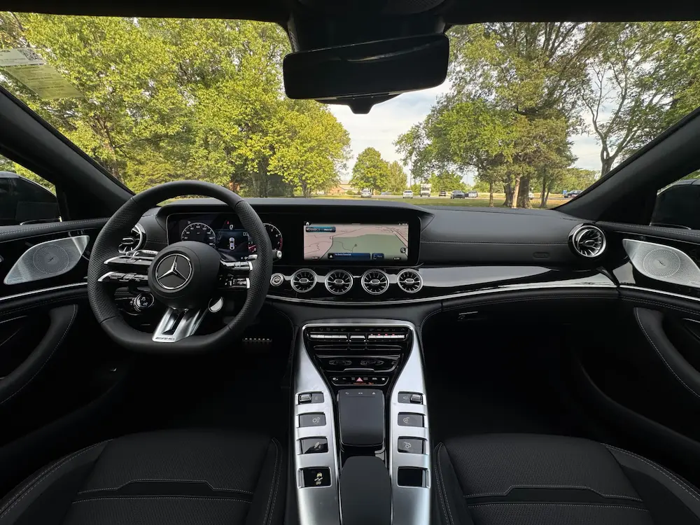 Interior of Mercedes-AMG GT 4-Door featuring digital cockpit, AMG steering wheel, and aluminum trim.
