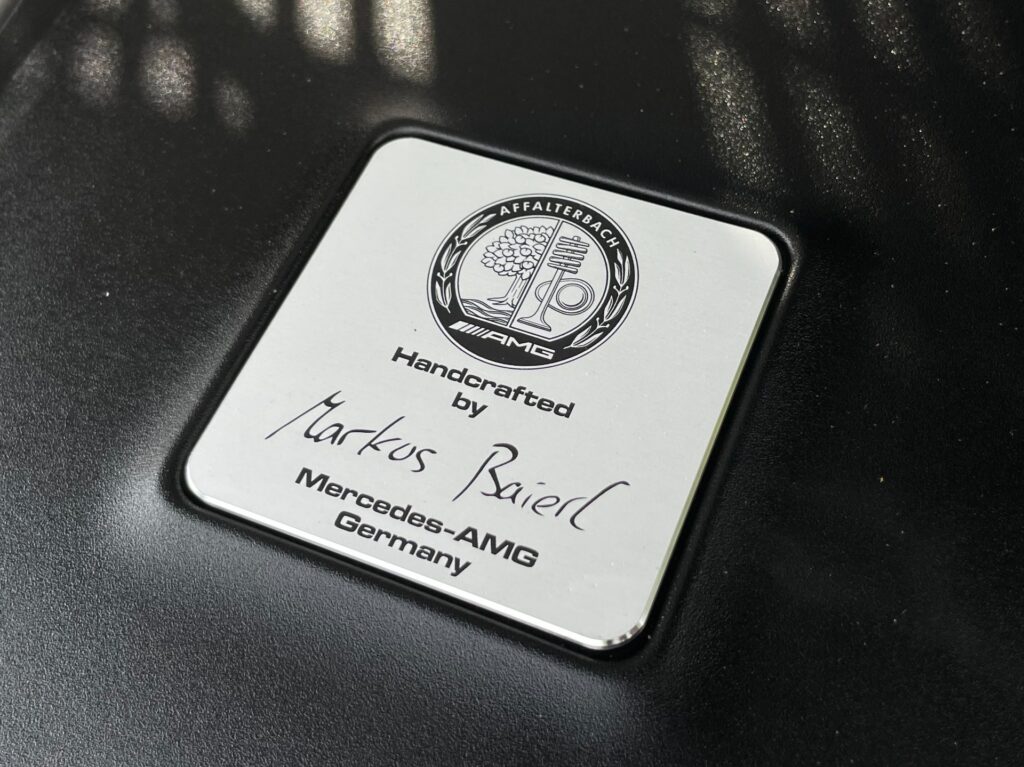 A silver plaque with the Mercedes-AMG logo, the inscription "Handcrafted by Markus Baierl," and the location "Affalterbach, Germany."