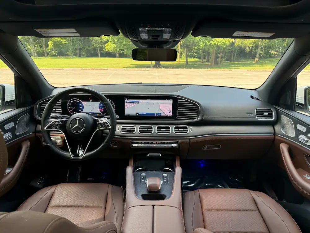Interior of Mercedes-Benz GLE SUV featuring dual widescreen displays, brown Nappa leather, and ambient lighting.