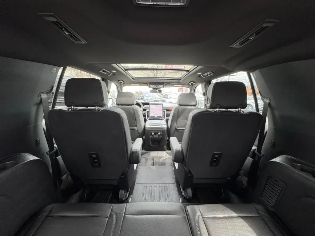 Interior rear cabin of the 2025 GMC Yukon XL Denali showing second and third-row seats with panoramic sunroof.