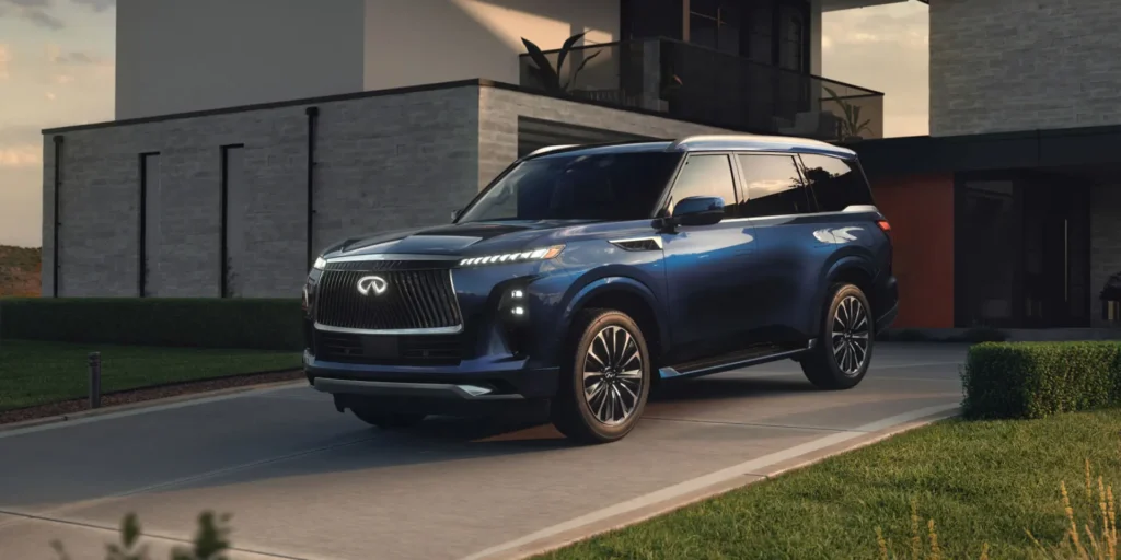 Blue 2025 Infiniti QX80 parked in front of a modern house.