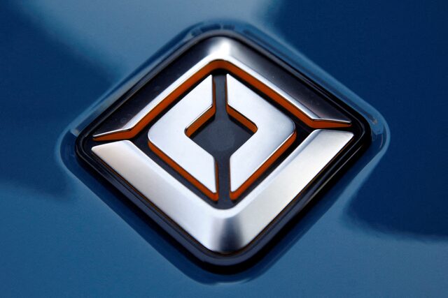 Close-up of a silver Rivian car logo on a blue background